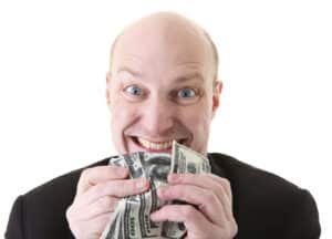 greed, businessman with money. man holding dollars in display of avarice isolated on white.